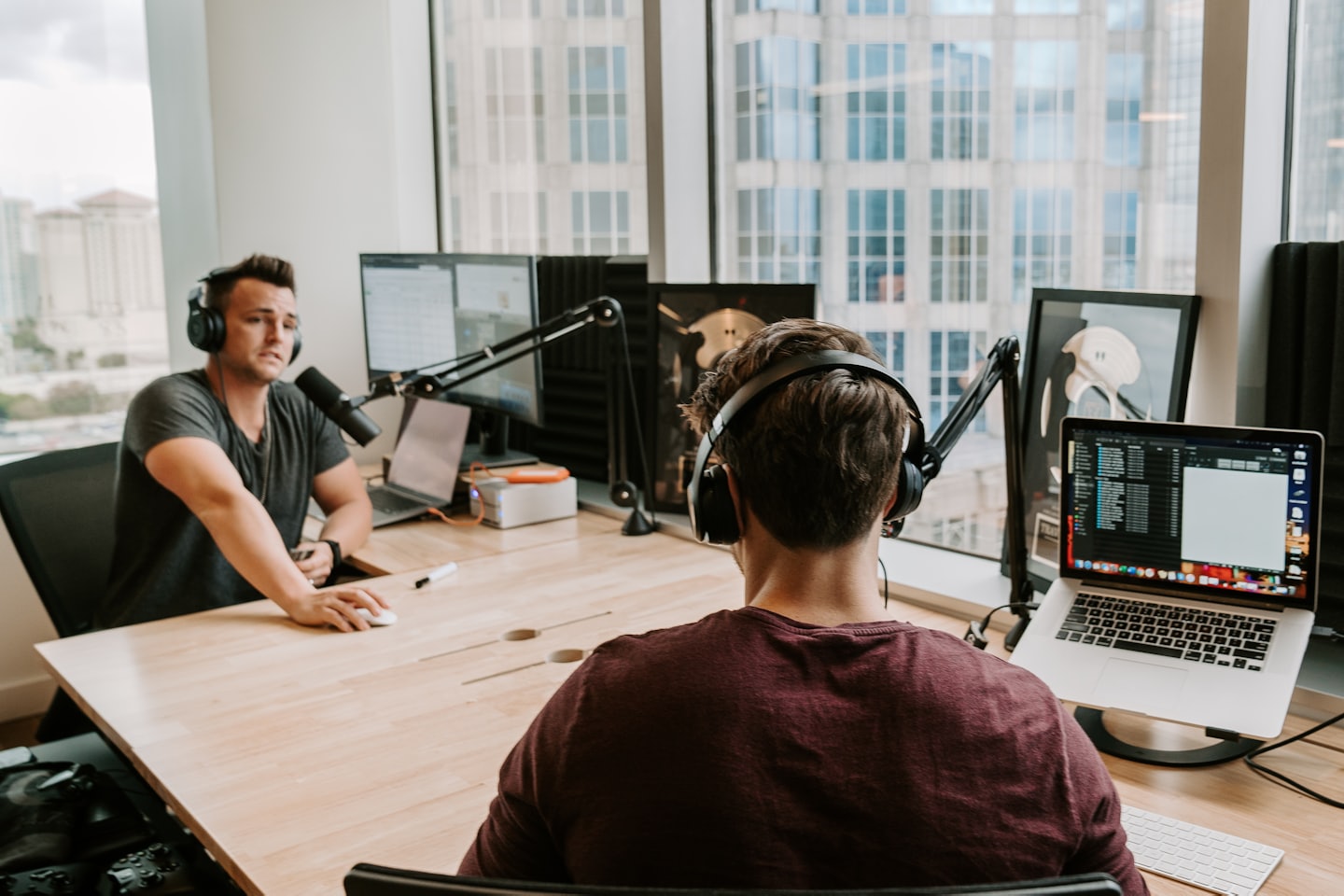 Due uomini in uno studio moderno registrano un podcast con vista sulla città.